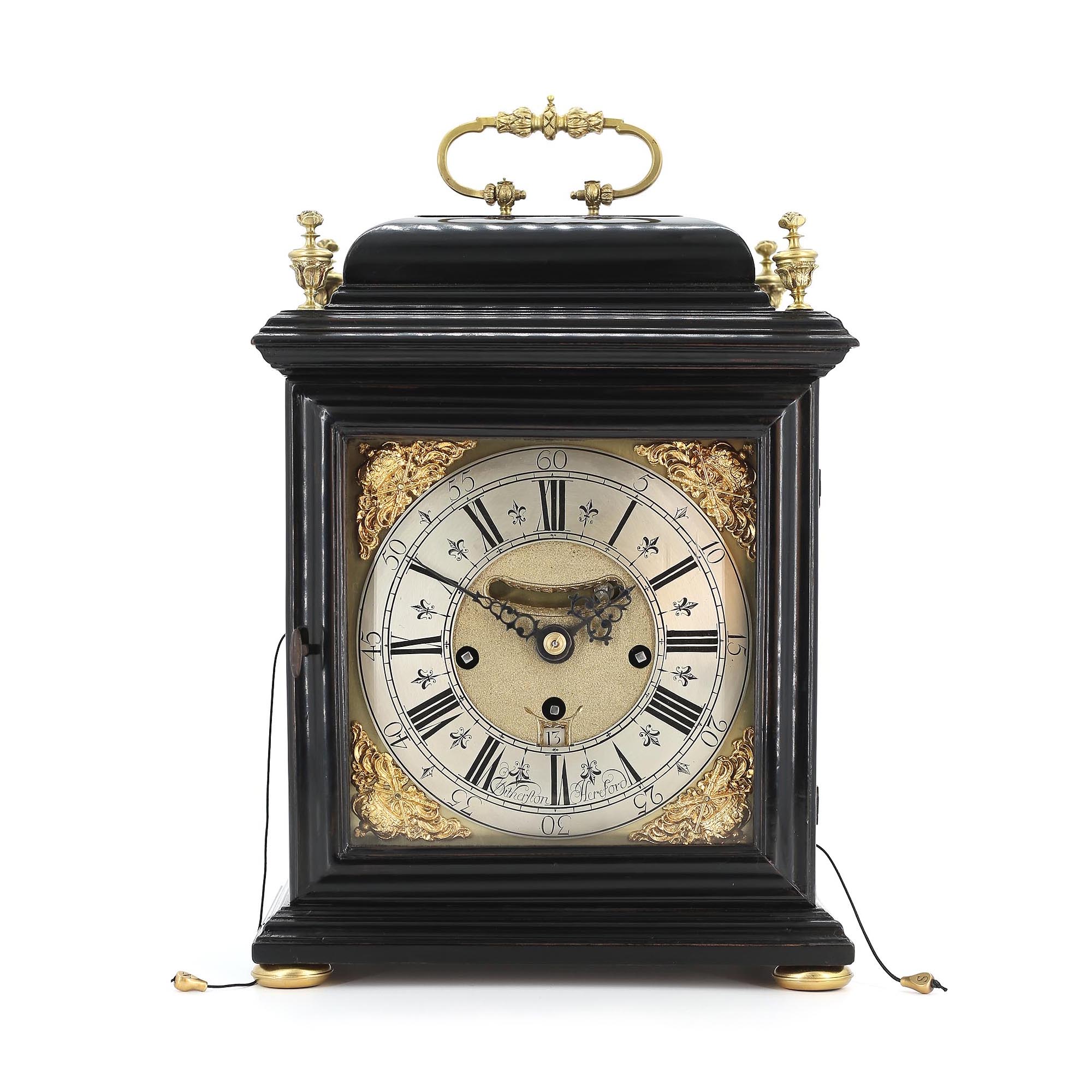 John Witherston of Hereford Quarter Striking Bracket Clock A rare, provincially made triple fusee bracket clock striking the hours on a bell, and the quarters on a nest of six bells. At each quarter, a peal runs down the bells, once on the quarter, twice on the half hour, and so on. 8-day, original verge escapement, with strike/silent on a string on either side of the case, allowing for operation without opening the case door. 7” finely matted brass dial with silvered chapter ring signed John Witherston of Hereford. Crown spandrels, a mock pendulum, and a square calendar box above the 6‘o’ clock position. Ebonised case, slightly smaller than standard, with finely cast handle, finials and feet. Glazed side windows, with cast brass, silk-backed sound frets just above the windows. Glazed rear door. John Witherston is listed as working from 1700 to 1734. C.1710-20 Height: 15 ½” or 38.5cm handle up. £28,500.00